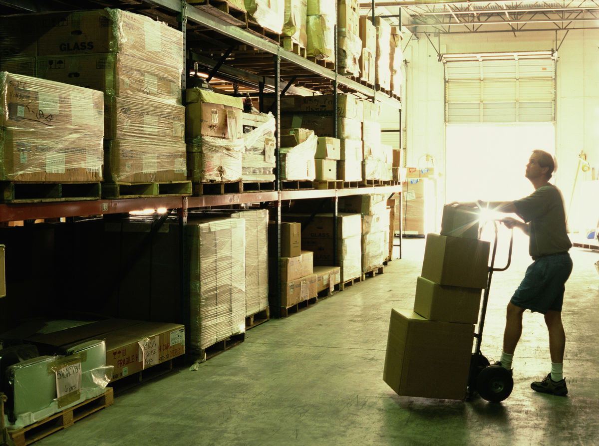 Warehouse worker with dolly full of boxes