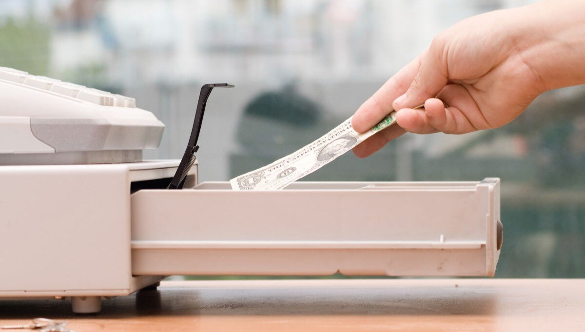 Money Being Placed In a Cash Register