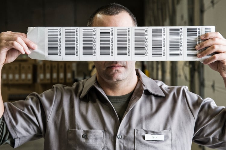 a-warehouse-worker-holding-up-a-sheet-of-bar-codes-1