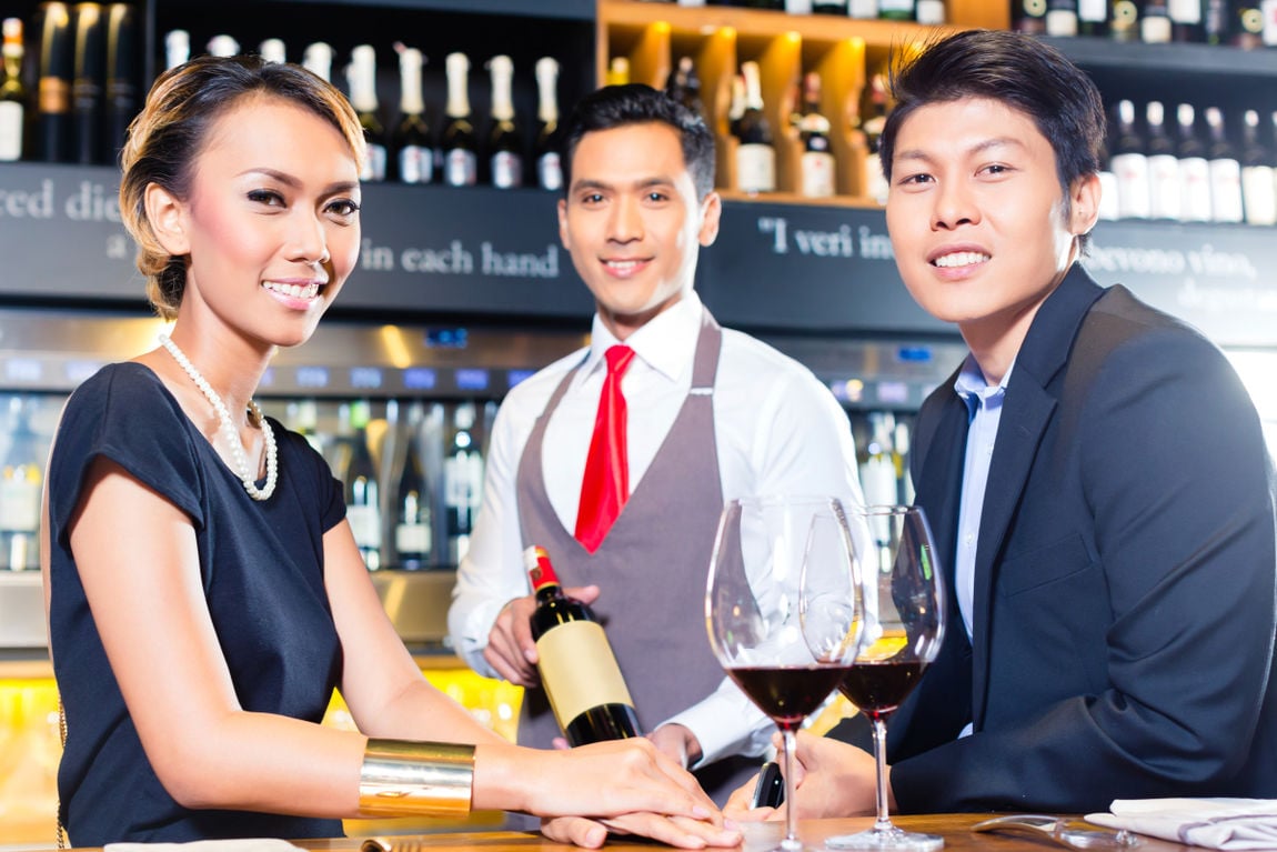 Asian couple tasting red wine in bar